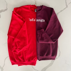 May include: Two sweatshirts, one red and one burgundy, with the text "'ofa'anga" printed in white on the front.
