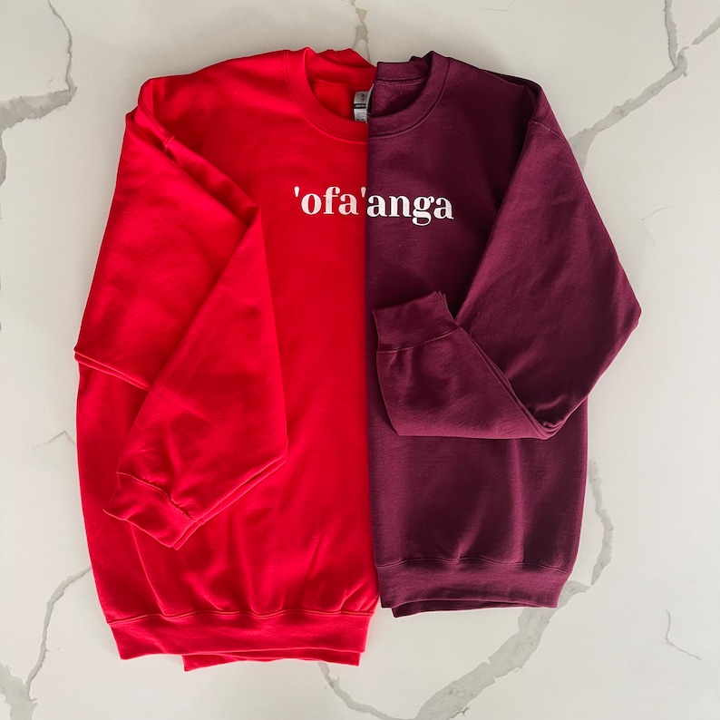 May include: Two sweatshirts, one red and one burgundy, with the text "'ofa'anga" printed in white on the front.