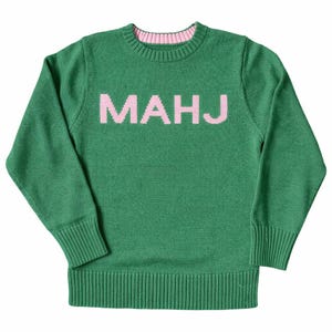 K&ouml;nnte beinhalten: Gr&uuml;ner Strickpullover mit dem Wort "MAHJ" in rosa Blockbuchstaben auf der Brust. Der Pullover hat einen gerippten Saum und B&uuml;ndchen sowie einen rosa Besatz um den Halsausschnitt. Der lang&auml;rmlige Pullover ist aus weichem Strickmaterial.
