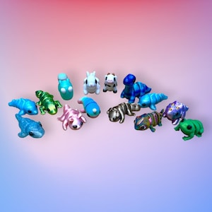 Op de afbeelding: Een verzameling van 15 kleine, kleurrijke, handgeschilderde beeldjes. De beeldjes zijn gemaakt van polymer clay en tonen een verscheidenheid aan dieren, waaronder een kikker, een hagedis, een koe, een geit, een dinosaurus en een rups.