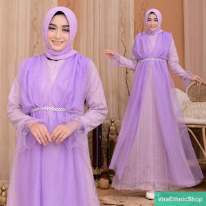 May include: A long, lilac-colored dress with a sheer overlay and a beaded belt. The dress has long sleeves with lace detailing and a flowing skirt.