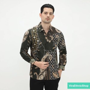 May include: A long-sleeved shirt with a green, black, and brown batik pattern. The shirt has a button-up collar and a button closure.