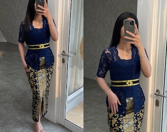 May include: A navy blue lace top with a gold and black patterned skirt. The top has a square neckline and short sleeves. A gold belt with a flower accent is worn around the waist.