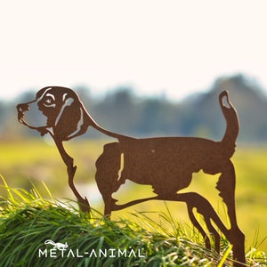 Könnte beinhalten: Eine rostige braune Metallsilhouette eines Beagle-Hundes, der in hohem grünem Gras steht. Die Silhouette ist aus Metall ausgeschnitten und hat ein detailliertes Design. Der Hintergrund ist verschwommen und unscharf. Der Text "METAL-ANIMAL" ist am unteren Rand des Bildes sichtbar.