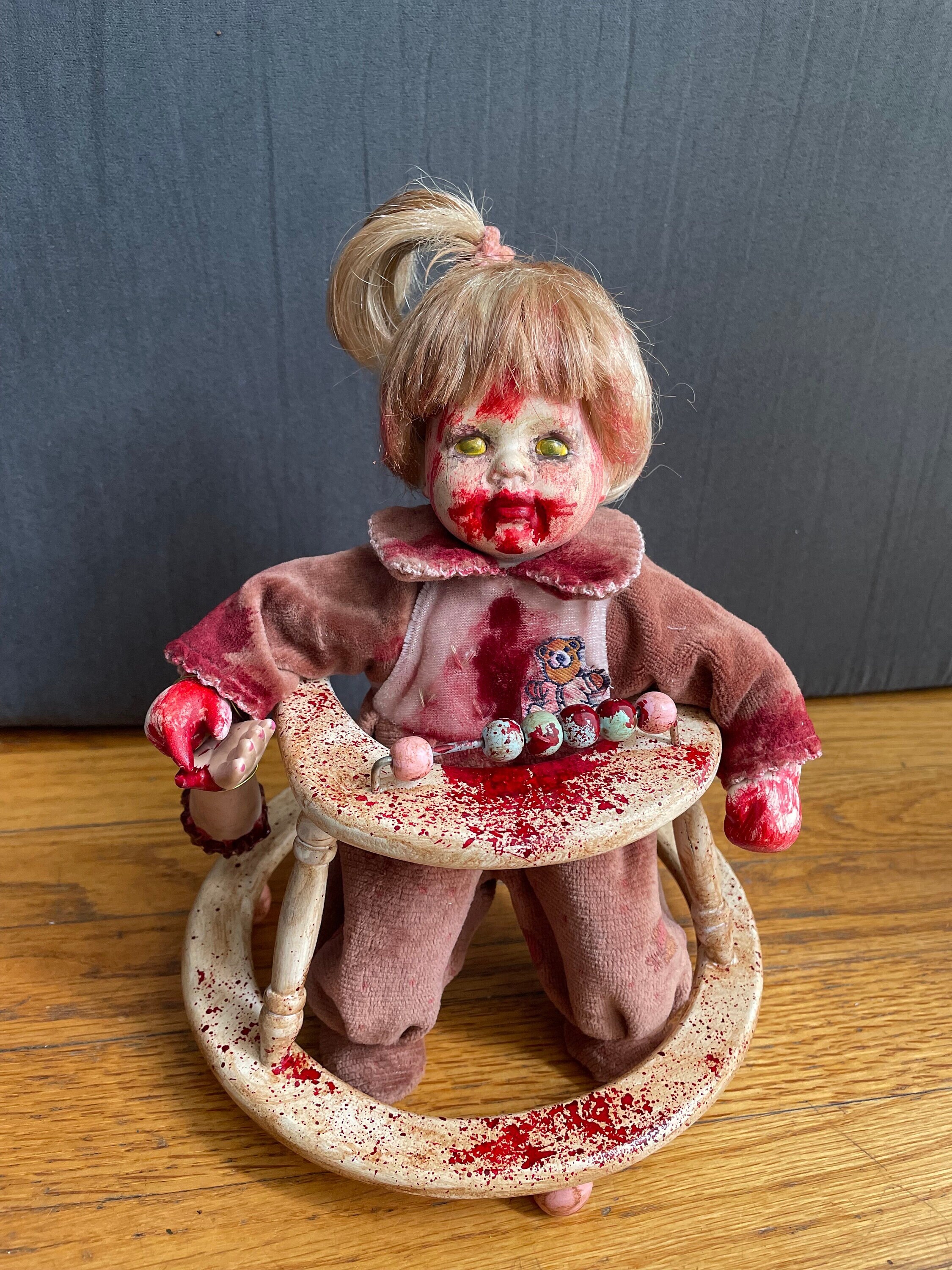 Bambola inquietante, bambino zombi sanguinante con girello
