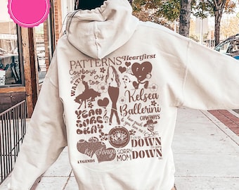 May include: A sand-colored hoodie with a graphic design featuring the text "PATTERNS", "Kelsea Ballerini", and other song lyrics. The design includes hearts, flowers, and a silhouette of a woman.