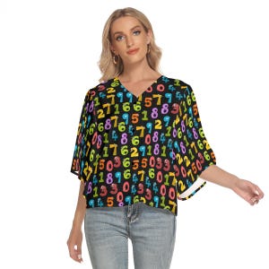 May include: A black V-neck top with a colorful number pattern. The top features a variety of numbers in different colors, creating a playful and eye-catching design. The sleeves are wide and the top is made of a lightweight material.