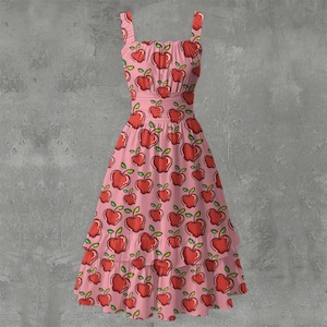 May include: A pink sundress with a repeating pattern of red apples with green leaves. The dress has a square neckline, adjustable straps, and a tiered skirt. The dress is approximately knee-length.