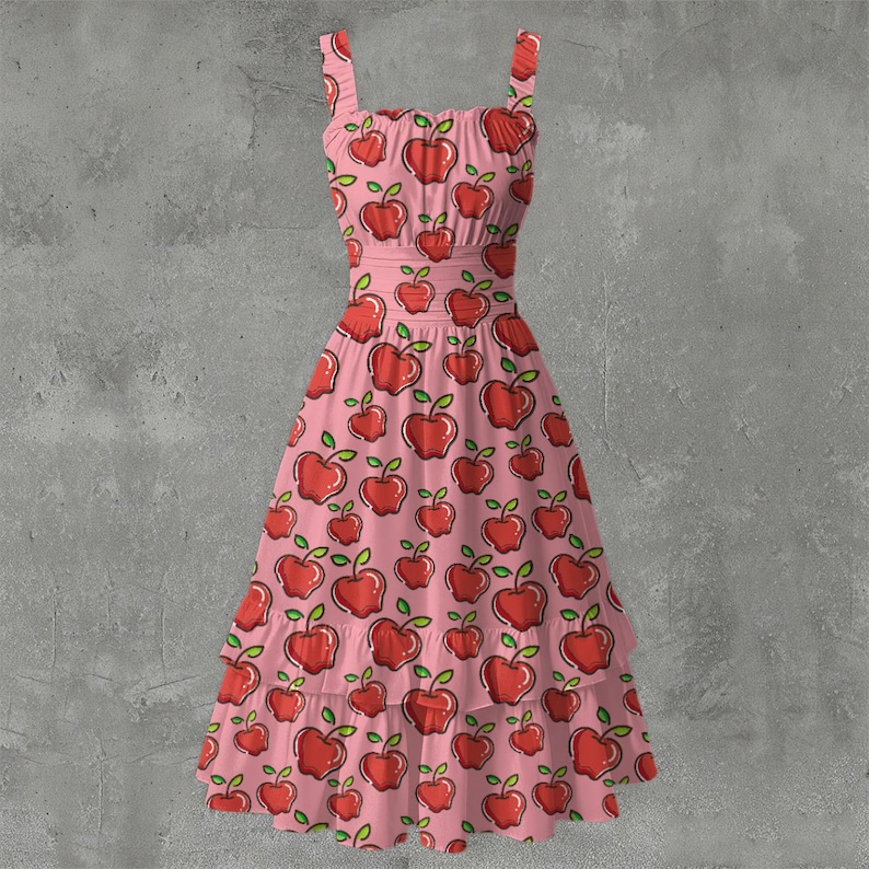 May include: A pink sundress with a repeating pattern of red apples with green leaves. The dress has a square neckline, adjustable straps, and a tiered skirt. The dress is approximately knee-length.