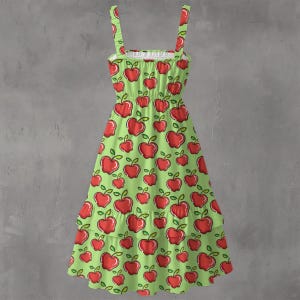 May include: A green sundress with a red apple pattern. The dress has a tiered skirt, spaghetti straps, and a white ruffled neckline. The apples have green leaves and stems.