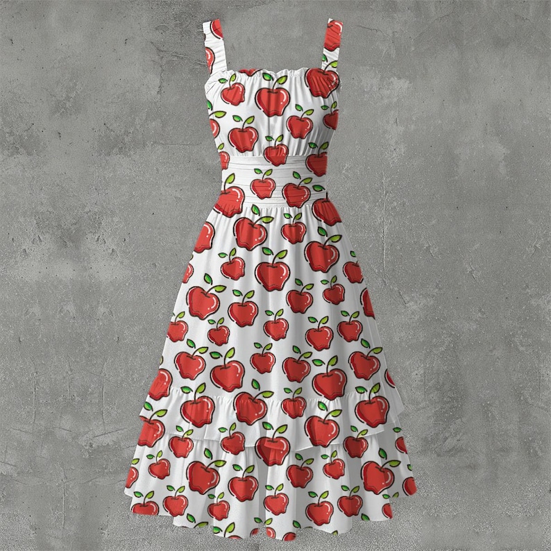 May include: White sundress with a red apple pattern. The dress features a square neckline, thin straps, and a tiered skirt. The apples have green leaves and are scattered across the fabric.