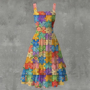 May include: A colorful patchwork dress featuring a puzzle piece design. The dress has a fitted bodice, a cinched waist with a floral accent, and a flowing skirt with a ruffled hem. The dress has adjustable straps.