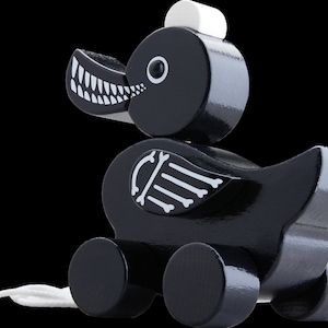 Op de afbeelding: Zwarte houten speelgoed eend met witte details. De eend heeft een skeletontwerp op zijn rug en wielen aan de onderkant. De eend heeft een wit trekkoord.