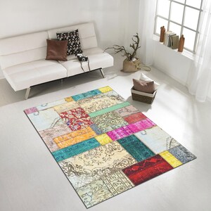 Op de afbeelding: Een kleurrijk patchwork tapijt met verschillende kleuren en patronen, waaronder rood, geel, blauw, groen en roze. Het tapijt is gemaakt van verschillende stoffen en texturen, wat een unieke en eclectische uitstraling geeft.