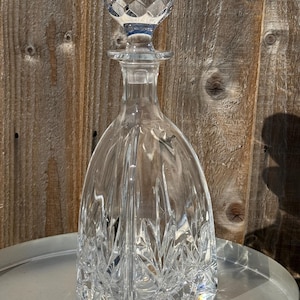 May include: A clear glass decanter with a faceted stopper. The decanter has a square base and a diamond-shaped pattern on the body.