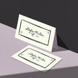 Plantilla de tarjeta de lugar de mesa dibujada a mano, decoración de mesa de recepción divertida y artística, ilustración de garabatos de corazón con moño caprichoso, fuente escrita a mano / CORJL