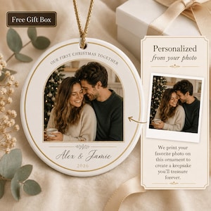 May include: A round white ceramic ornament featuring a gold-rimmed photo of a couple, the text "OUR FIRST CHRISTMAS TOGETHER", "Alex & Jamie", and "2026". The ornament hangs from a gold cord and includes a card explaining the photo printing process.