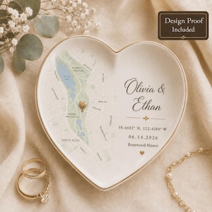 May include: A heart-shaped white ceramic trinket dish featuring a printed map of Santa Rosa with a gold heart marker. The text reads Olivia & Ethan, 38.4652 N, 122.4286 W, 06.14.2026, and Rosewood Manor. A gold-rimmed edge completes the design.