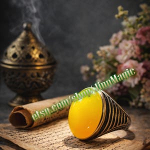 May include: A silver ring with a large, oval, yellow gemstone. The ring has a black striped design on the band. The image also includes a decorative incense burner, a scroll, and flowers. The text "etsy.com/shop/linnMagic" is visible.