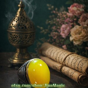 May include: A gold-colored incense burner with smoke rising, a large yellow gemstone ring, and rolled parchment scrolls. The ring has a silver band. The background features flowers and a dark green wall.