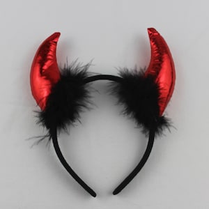 May include: Red devil horns headband with black feather trim. The headband is black and has a simple design.
