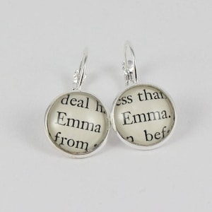 May include: Silver hoop earrings with a round glass charm featuring a printed excerpt from the book "Emma" by Jane Austen. The text reads "deal h. Emma from."
