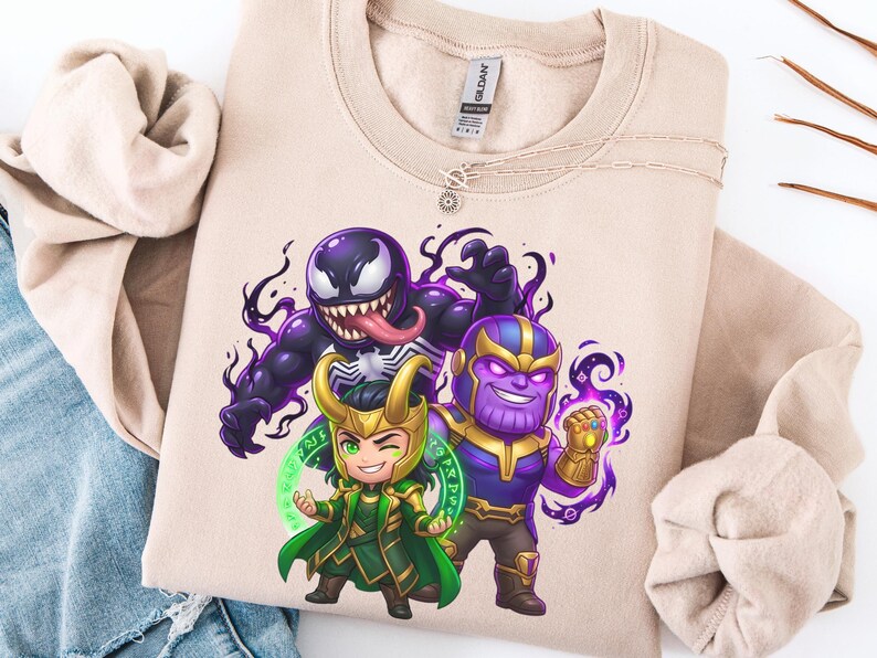 May include: Beige crewneck sweatshirt featuring a colorful graphic of Venom, Loki, and Thanos in a cartoon style. The characters are depicted with exaggerated features and surrounded by swirling purple and green energy.