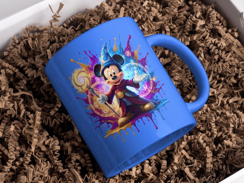 May include: A blue ceramic mug with a colourful illustration of Mickey Mouse as a wizard. The design includes a wizard's hat, staff, and magical symbols. The mug is set against a background of brown packing material.