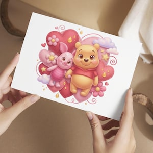 K&ouml;nnte beinhalten: Eine Gru&szlig;karte mit einer Cartoon-Illustration von Winnie Puuh und Ferkel. Die Charaktere sind von rosa und roten Herzen, Blumen, Sternen und Wolken umgeben. Die Karte wird von einer Person gehalten.