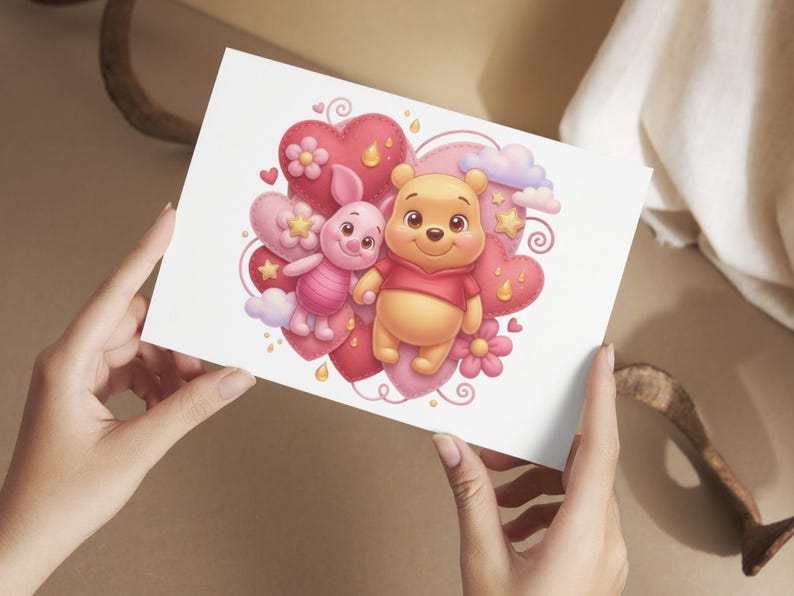 K&ouml;nnte beinhalten: Eine Gru&szlig;karte mit einer Cartoon-Illustration von Winnie Puuh und Ferkel. Die Charaktere sind von rosa und roten Herzen, Blumen, Sternen und Wolken umgeben. Die Karte wird von einer Person gehalten.