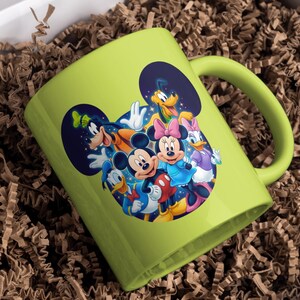 May include: A lime green ceramic mug featuring a colorful graphic of Mickey Mouse, Minnie Mouse, Donald Duck, Daisy Duck, Goofy, and Pluto. The mug is inside a white box with brown paper filler.