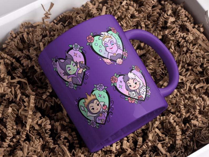 May include: A purple ceramic mug featuring four heart-shaped illustrations of Disney villains. Each heart has a different villain, surrounded by floral and decorative elements. The mug is in a gift box with brown paper filler.