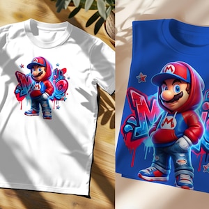 May include: White t-shirt featuring a colorful graphic of a cartoon character in a red and blue outfit, with the word "Mario" in graffiti style. The character is wearing a red cap and hoodie. A second blue t-shirt with the same design is also shown.