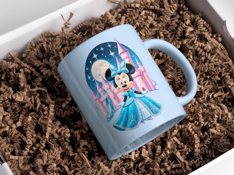May include: A light blue ceramic mug with a colorful illustration of Mickey Mouse dressed as a princess in front of a castle. The background is a night sky with stars and a moon.