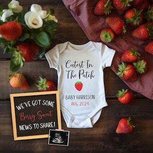 Puede incluir: Un body blanco para bebé con el texto "Cutest In The Patch" y un gráfico de fresa roja. El body tiene el texto "Baby Harrison Aug. 2024" impreso debajo del gráfico. Un tablero de letras negro con el texto "We've got some Berry Sweet news to share!" está en la imagen. El body y el tablero de letras están rodeados de fresas rojas.