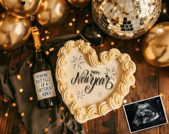 May include: A heart-shaped cake decorated with the words "Happy New Year" and fireworks. The cake is surrounded by gold and black balloons, including one that says "Baby Weston" and another that says "Jan. 2025". There is also a bottle of champagne with a label that says "Poppin' Bottles of a Different Kind!" and a black and white ultrasound image.