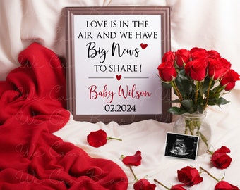 May include: A framed announcement card with the text "Love is in the air and we have Big News to share! Baby Wilson 02.2024" surrounded by red roses and a sonogram image.
