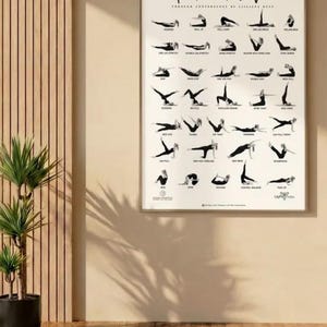Peut inclure: Affiche encadrée avec le texte "Return to Life" et des poses de yoga noires sur fond blanc. L'affiche est accrochée sur un mur beige, à côté d'une plante en pot et d'un panneau en bois.