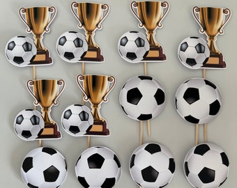 Puede incluir: Doce toppers de cupcake de trofeo dorado con un diseño de balón de fútbol. Los toppers están hechos de cartón y tienen un palo de madera pegado en la parte posterior.