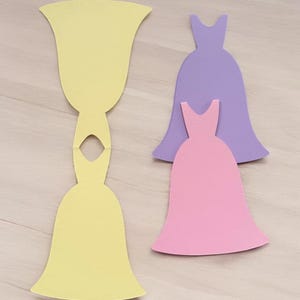 Pu&ograve; includere: Tre sagome di abiti di carta, uno giallo, uno rosa e uno viola. L'abito giallo &egrave; diviso a met&agrave;, con la parte superiore separata dalla parte inferiore.