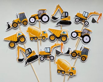 Puede incluir: Un conjunto de 10 adornos para cupcakes de vehículos de construcción amarillos. Los adornos presentan una variedad de vehículos, incluyendo excavadoras, camiones de volteo, mezcladoras de cemento y tractores. Los adornos son perfectos para una fiesta con temática de construcción.