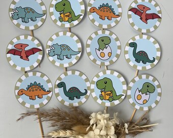 Puede incluir: Conjunto de 10 adornos para cupcakes con temática de dinosaurios. Cada adorno presenta un diseño de dinosaurio diferente con varios colores, incluidos el verde, el azul, el rojo y el marrón. Los adornos están impresos en cartulina blanca y tienen un palo pegado en la parte posterior.