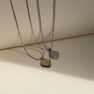 Pu&ograve; includere: Due delicate collane con ciondoli a forma di cuore. La collana dorata presenta un piccolo design di uccello sul ciondolo. La collana d'argento ha un ciondolo con l'iscrizione "Till the day that I die."
