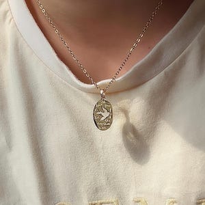 Peut inclure: Un collier en cha&icirc;ne dor&eacute;e avec un pendentif ovale en or. Le pendentif pr&eacute;sente un petit motif d'oiseau et les mots "Je t'aimerai jusqu'au jour de ma mort".