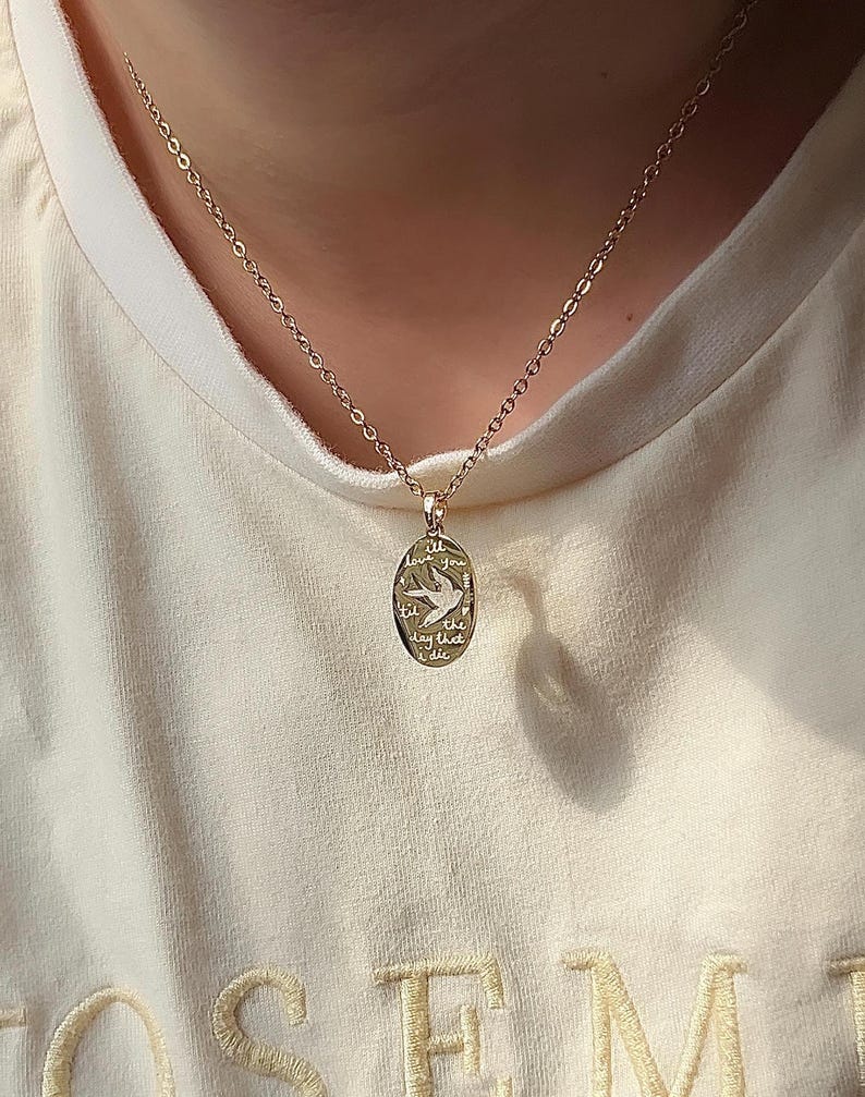 Peut inclure: Un collier en cha&icirc;ne dor&eacute;e avec un pendentif ovale en or. Le pendentif pr&eacute;sente un petit motif d'oiseau et les mots "Je t'aimerai jusqu'au jour de ma mort".