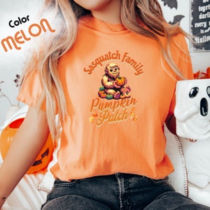 May include: Orange t-shirt with a graphic of a sasquatch family holding pumpkins and the text "Sasquatch Family Pumpkin Patch".