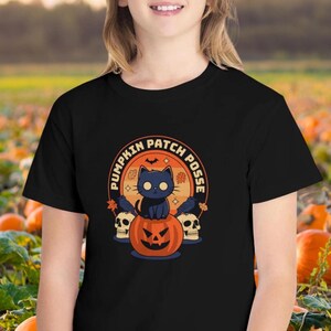 May include: Black t-shirt featuring a graphic of a black cat sitting on a jack-o'-lantern. The graphic is surrounded by a circle with the text "Pumpkin Patch Posse".