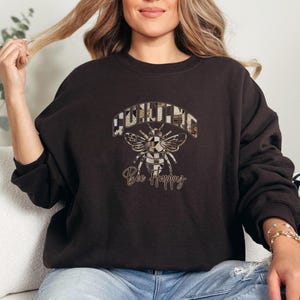 May include: A black sweatshirt with a graphic of a bee with the words "Quilting Bee Happy" printed on it.