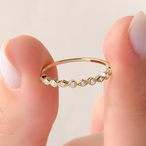 May include: A delicate gold band ring with a row of small, round diamonds.