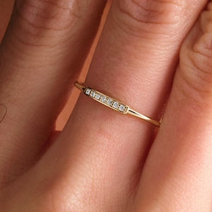 May include: A delicate gold ring with a row of small diamonds set in a curved band.